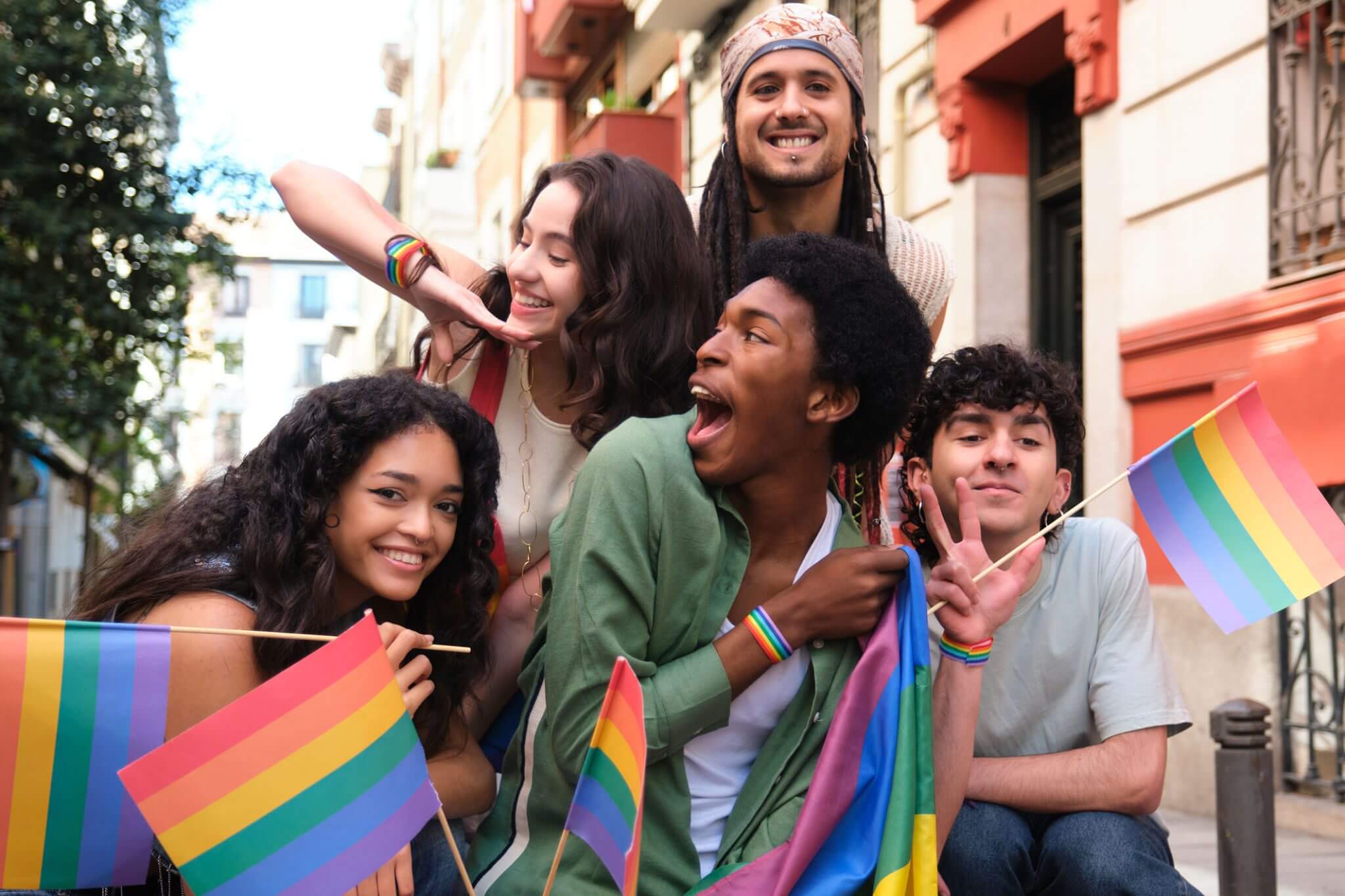 Group celebrating with pride flags, smiling outdoors.
