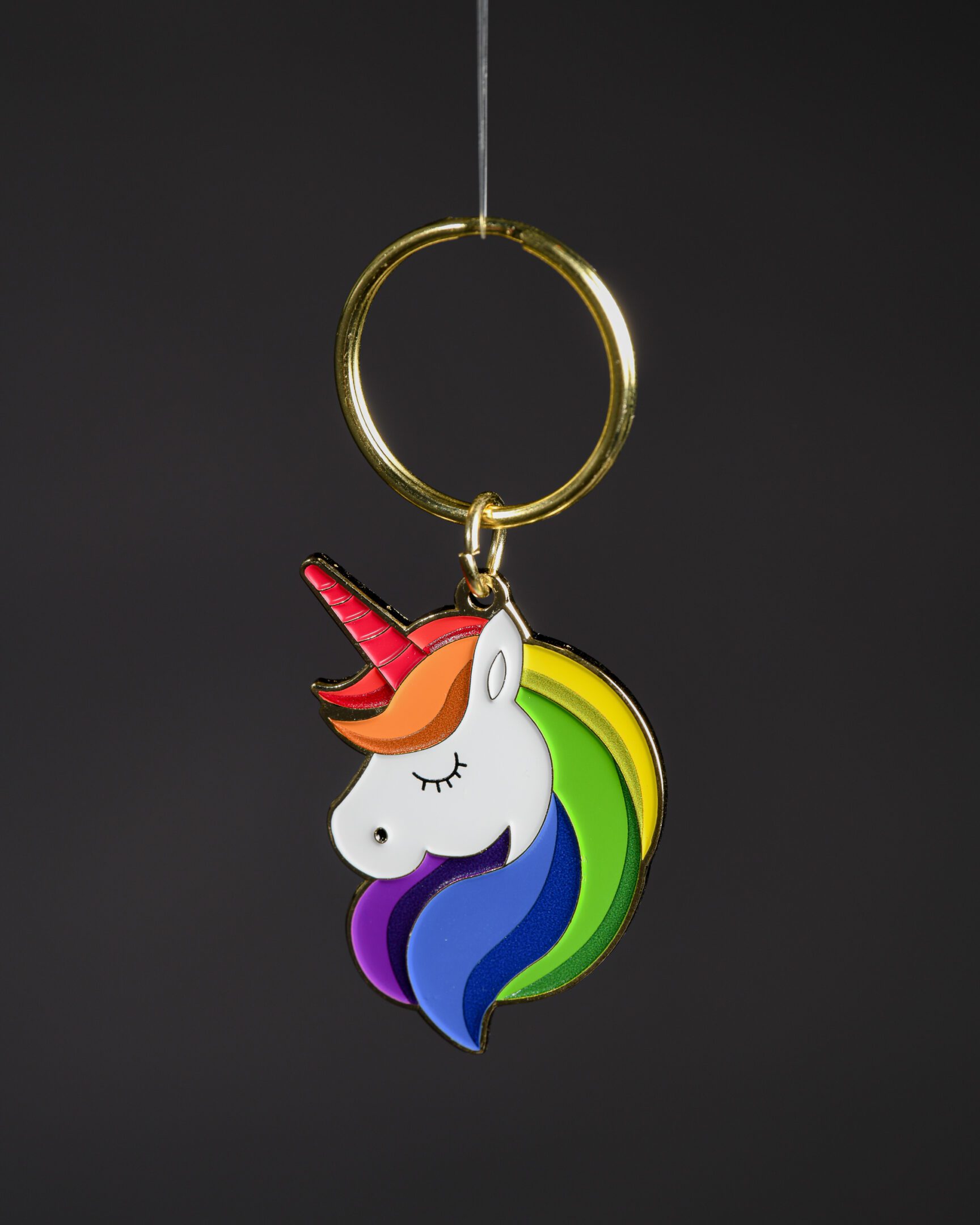 Colorful unicorn keychain on dark background.