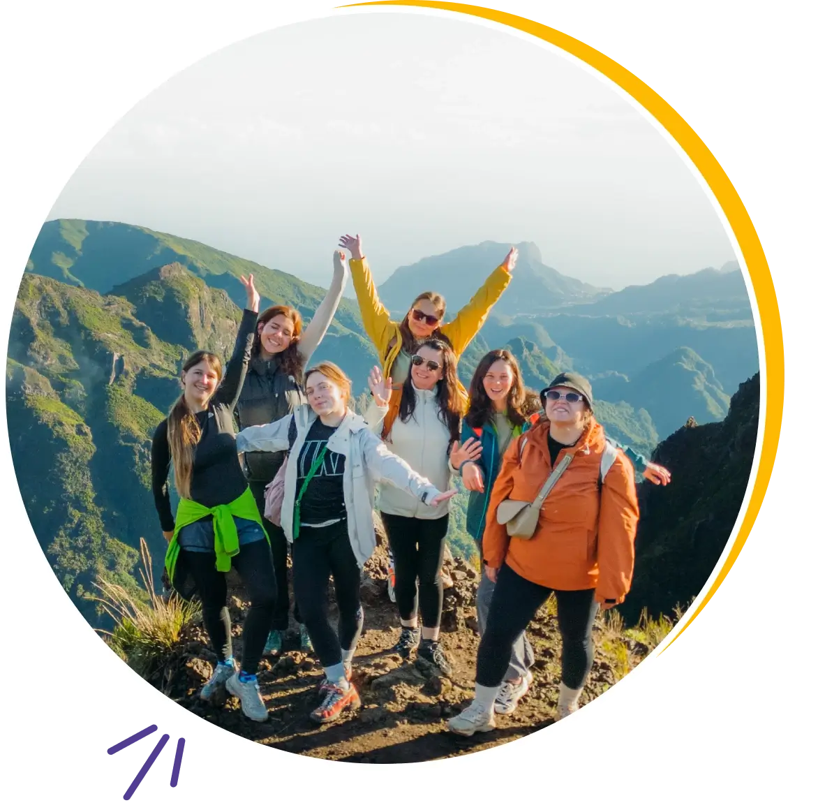 Group of friends celebrating on a mountain peak at sunrise.